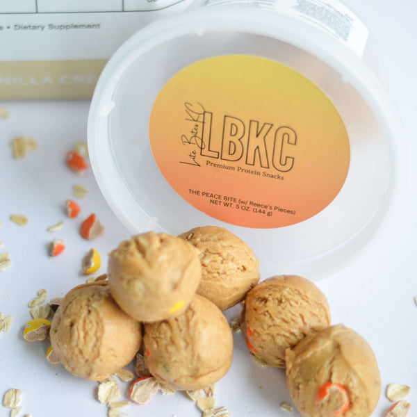 Protein bites scattered on a table with reeses's pieces and a plastic container