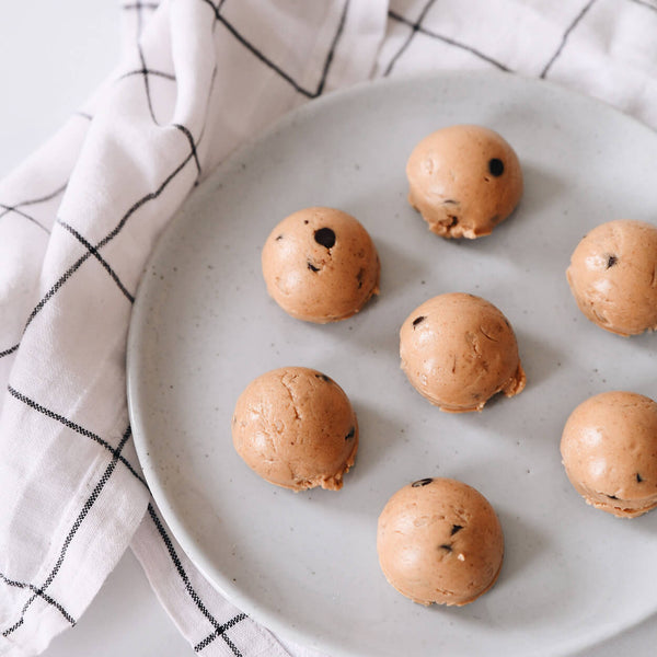 Chocolate peanut butter protein bites on a plate with a black and white striped tea towel in the background