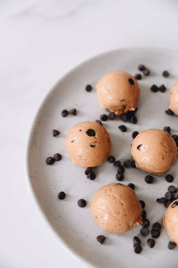 Chocolate peanut butter protein bites on a plate with chocolate chips scattered around