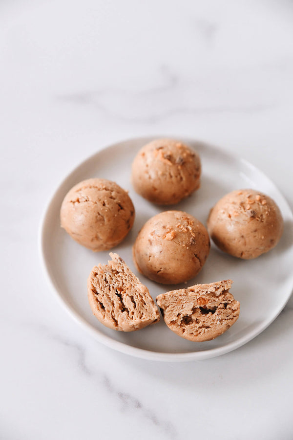 Protein bites scattered on a plate sprinkled with butterfinger pieces.