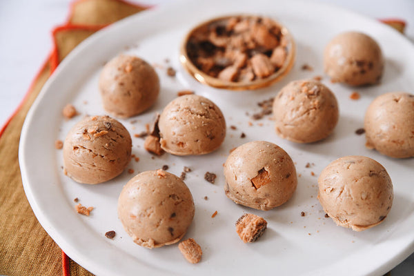 Protein bites scattered on a plate sprinkled with butterfinger pieces.
