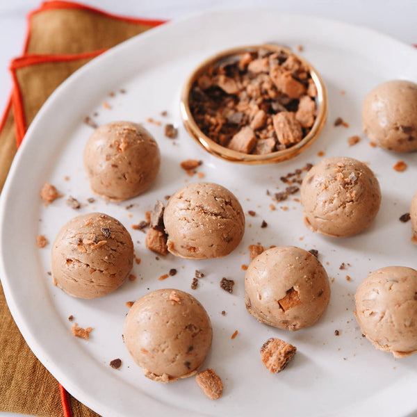 Protein bites scattered on a plate sprinkled with butterfinger pieces.