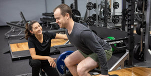 Person exercising with a personal trainer in a gym setting
