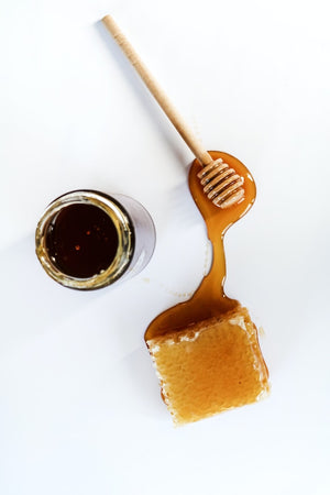 Honeycomb and honey jar on white background